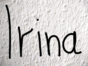 Der Name Irina handschriftlich geschrieben auf einem Hintergrund aus Raufasertapete